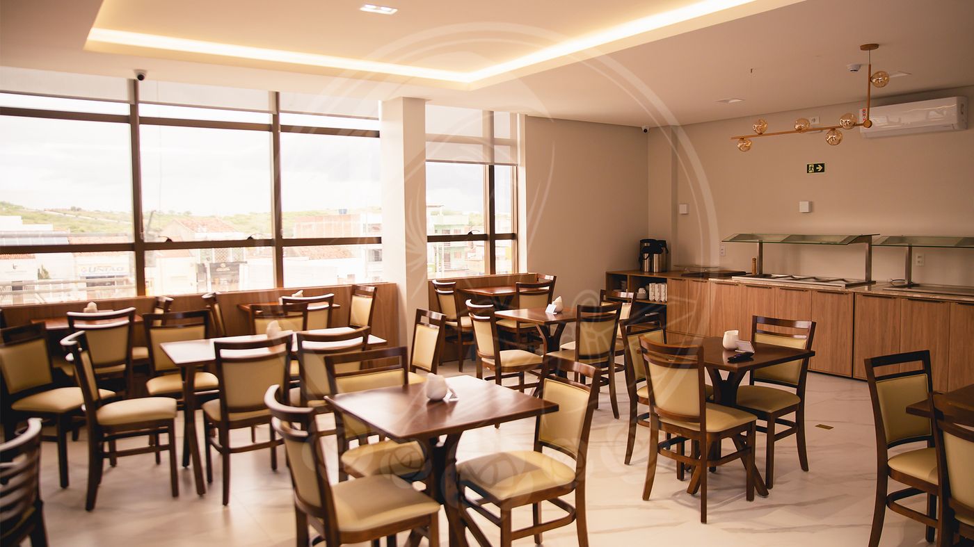 Salão do café da manhã com mesas de madeira e janelas amplas