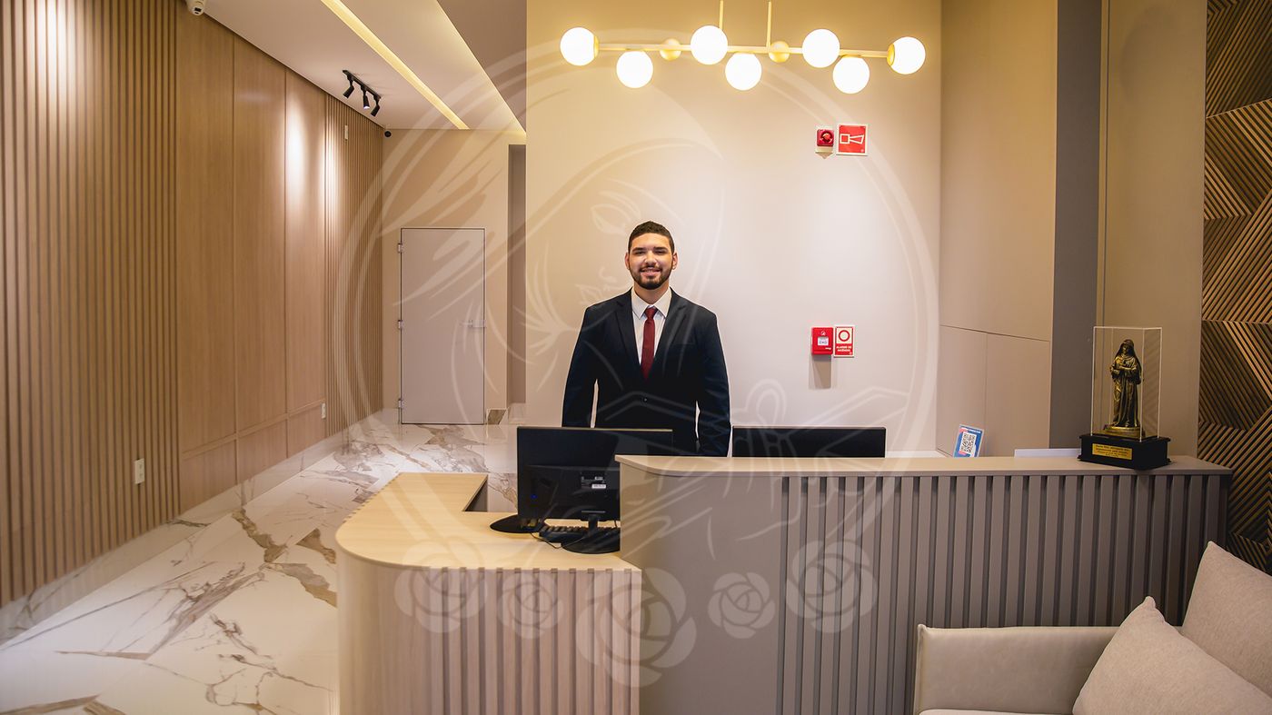 Recepção do Hotel Santa Rita, com balcão de madeira clara e atendente sorrindo